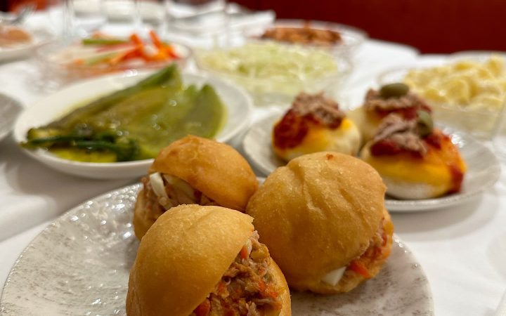 Trois petits pains fricassés garnis de thon et d'ingrédients sont présentés sur une assiette en céramique