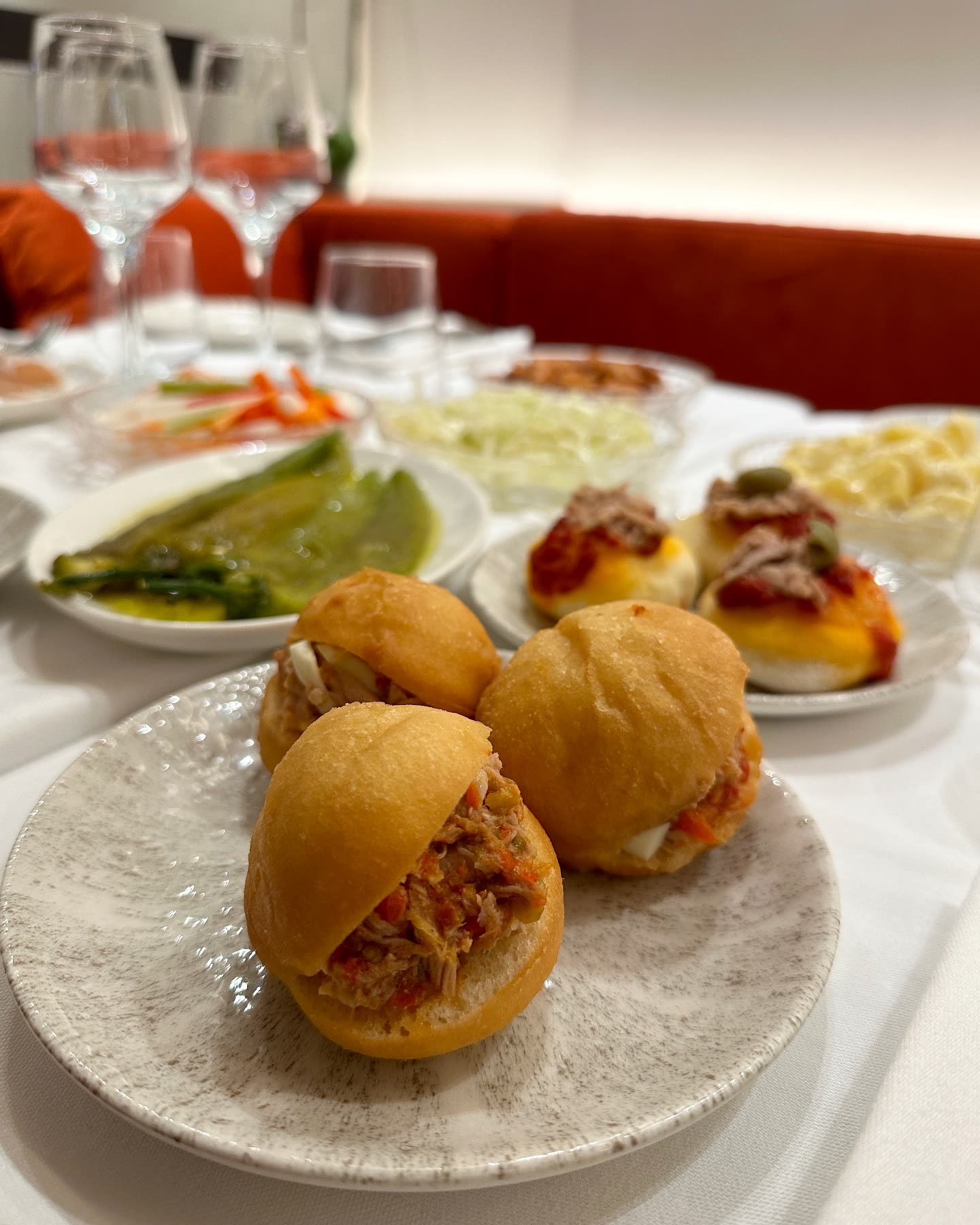 Trois petits pains fricassés garnis de thon et d'ingrédients sont présentés sur une assiette en céramique