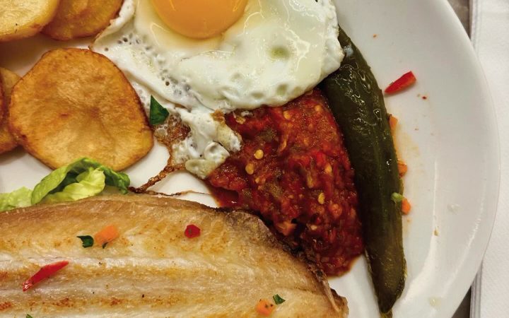 Un filet de poisson grillé accompagné d'un œuf au plat, de pommes de terre et de légumes