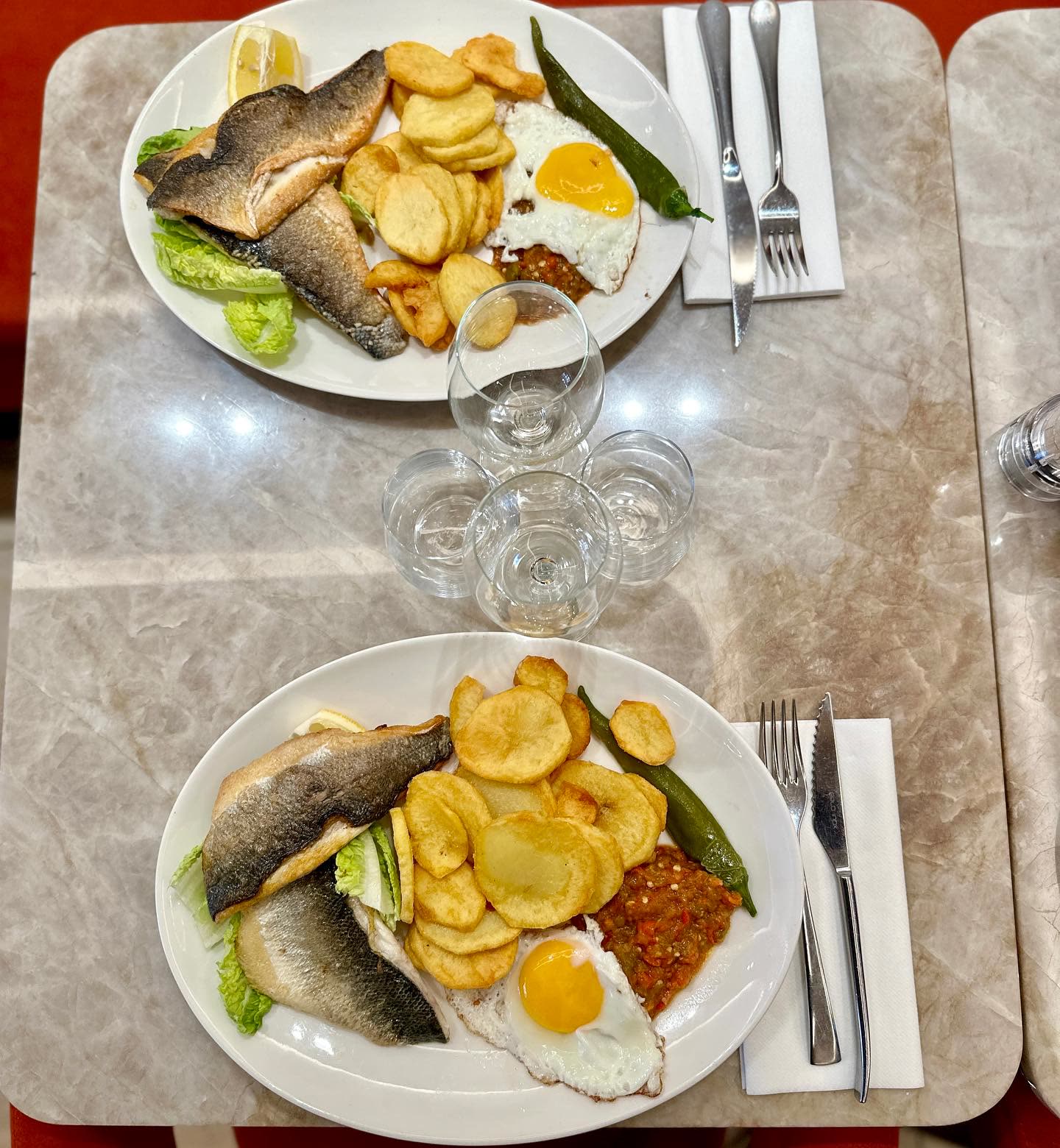 Deux assiettes de poisson grillé accompagnées de pommes de terre et d'un œuf au plat