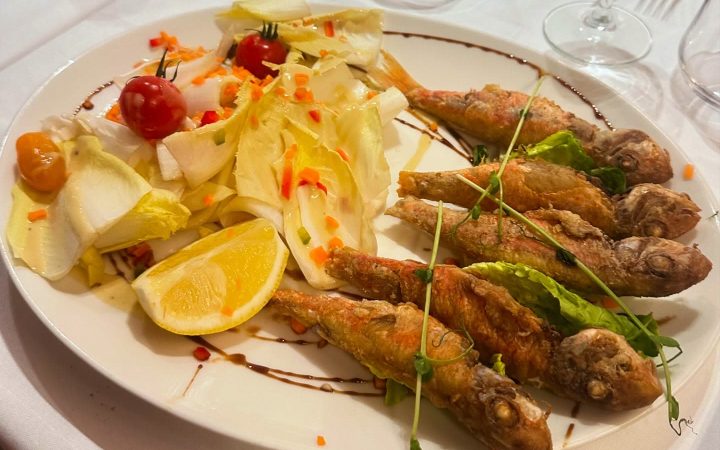 Un plat de poissons frits accompagné d'une salade composée et d'un quartier de citron