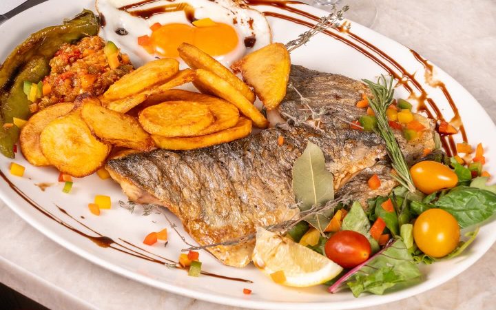 Un plat de poisson grillé accompagné de pommes de terre et de légumes