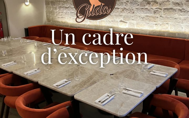 Une salle de restaurant avec des tables dressées, des chaises rouges et un logo sur un mur en pierre