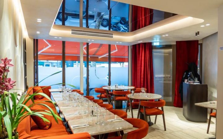L'intérieur d'un restaurant avec des tables, des chaises orange et un plafond avec un miroir