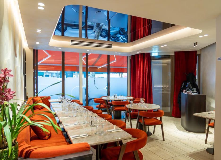 L'intérieur d'un restaurant avec des tables, des chaises orange et un plafond avec un miroir