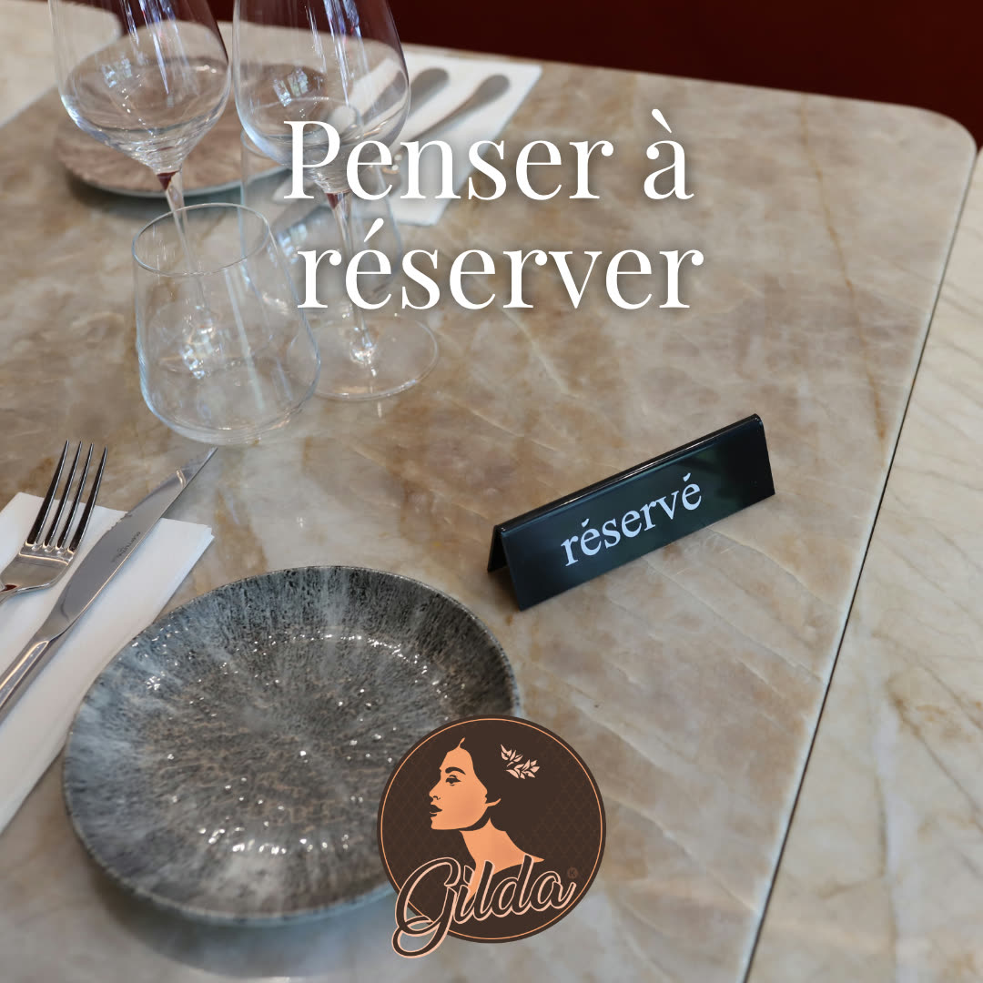 Une table dressée avec des verres, des couverts et un panneau de réservation