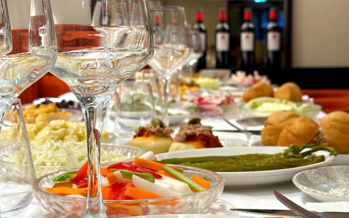 Une table dressée avec divers plats de kemia, des verres à vin et des assiettes de crudités