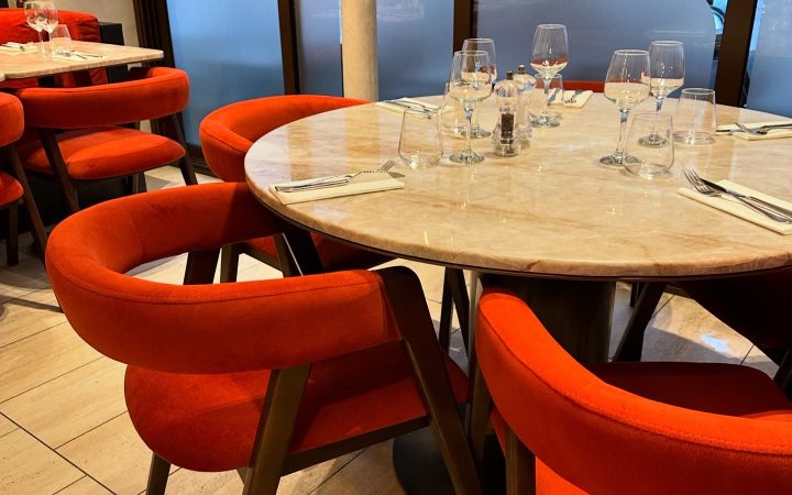 Une table ronde en marbre dressée avec des verres dans un restaurant