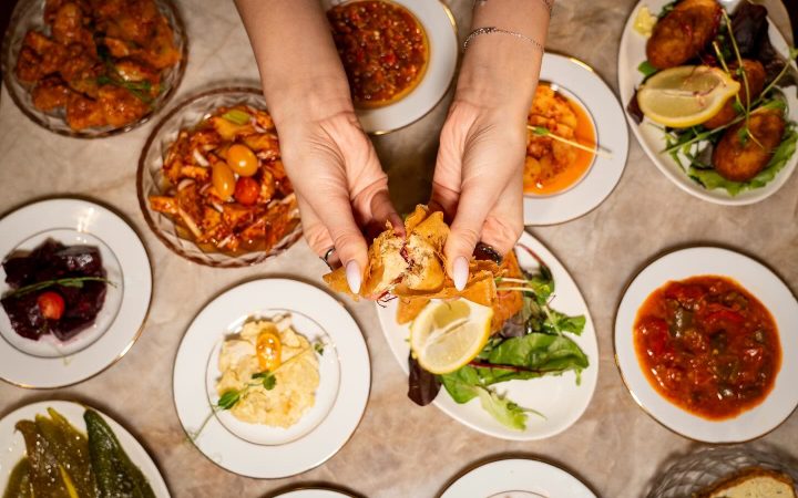 Une vue de dessus d'une table garnie de nombreux plats de cuisine tunisienne avec des mains tenant un morceau de pain